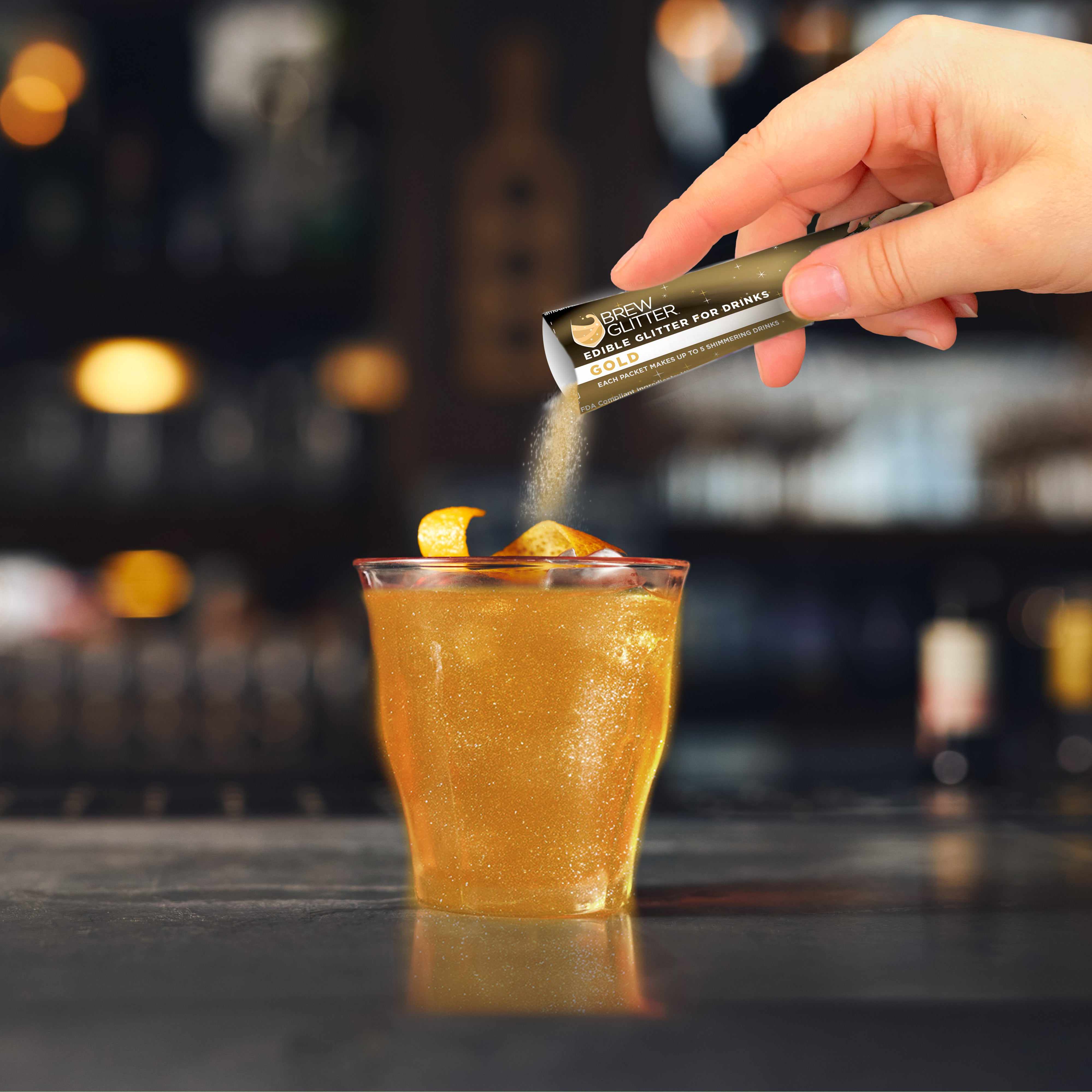 using a glitter stick onto an orange shimmer cocktail