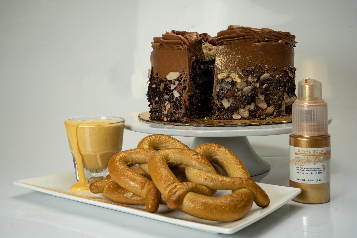 Chocolate cake with gold edible glitter, pretzels, cheese dip, and a bottle of Royal Gold edible glitter.