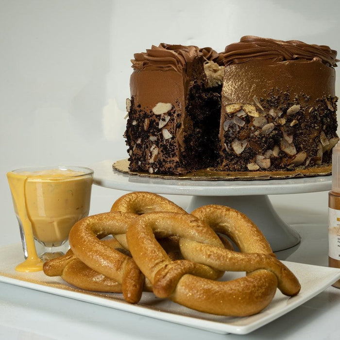 Chocolate cake with gold edible glitter, pretzels, cheese dip, and a bottle of Royal Gold edible glitter.