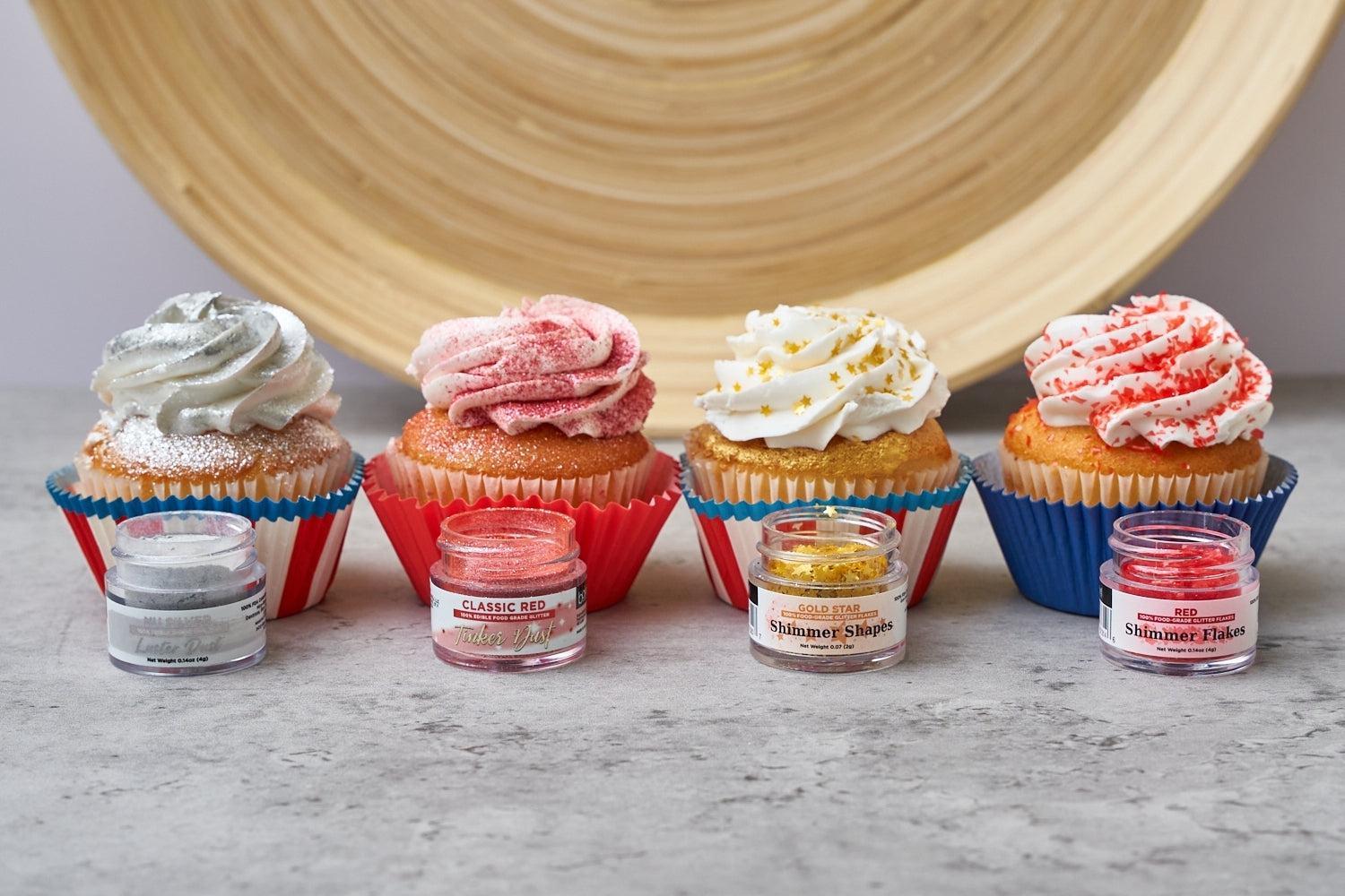 Four festive cupcakes with silver, pink, gold, and red edible glitter and sprinkles, alongside matching jars.