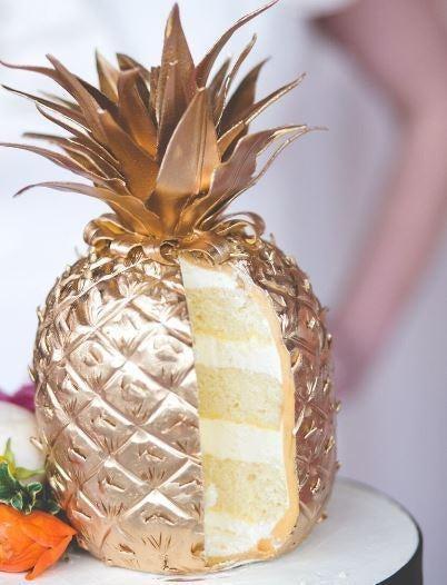 Elegant golden pineapple cake with a slice removed, revealing white and yellow layers.