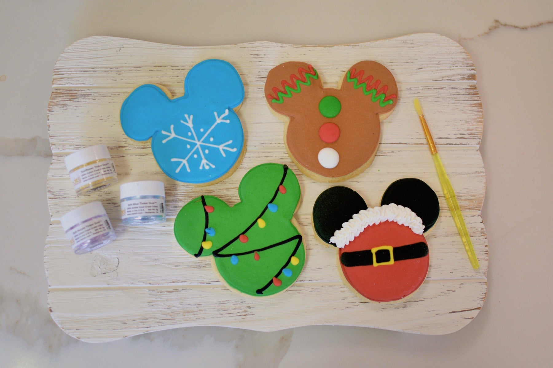 Mickey Mouse-shaped Christmas cookies: snowflake, gingerbread man, decorated tree, and Santa suit designs.