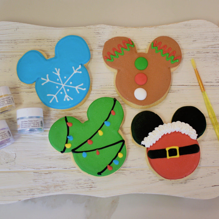 Mickey Mouse-shaped Christmas cookies: snowflake, gingerbread man, decorated tree, and Santa suit designs.