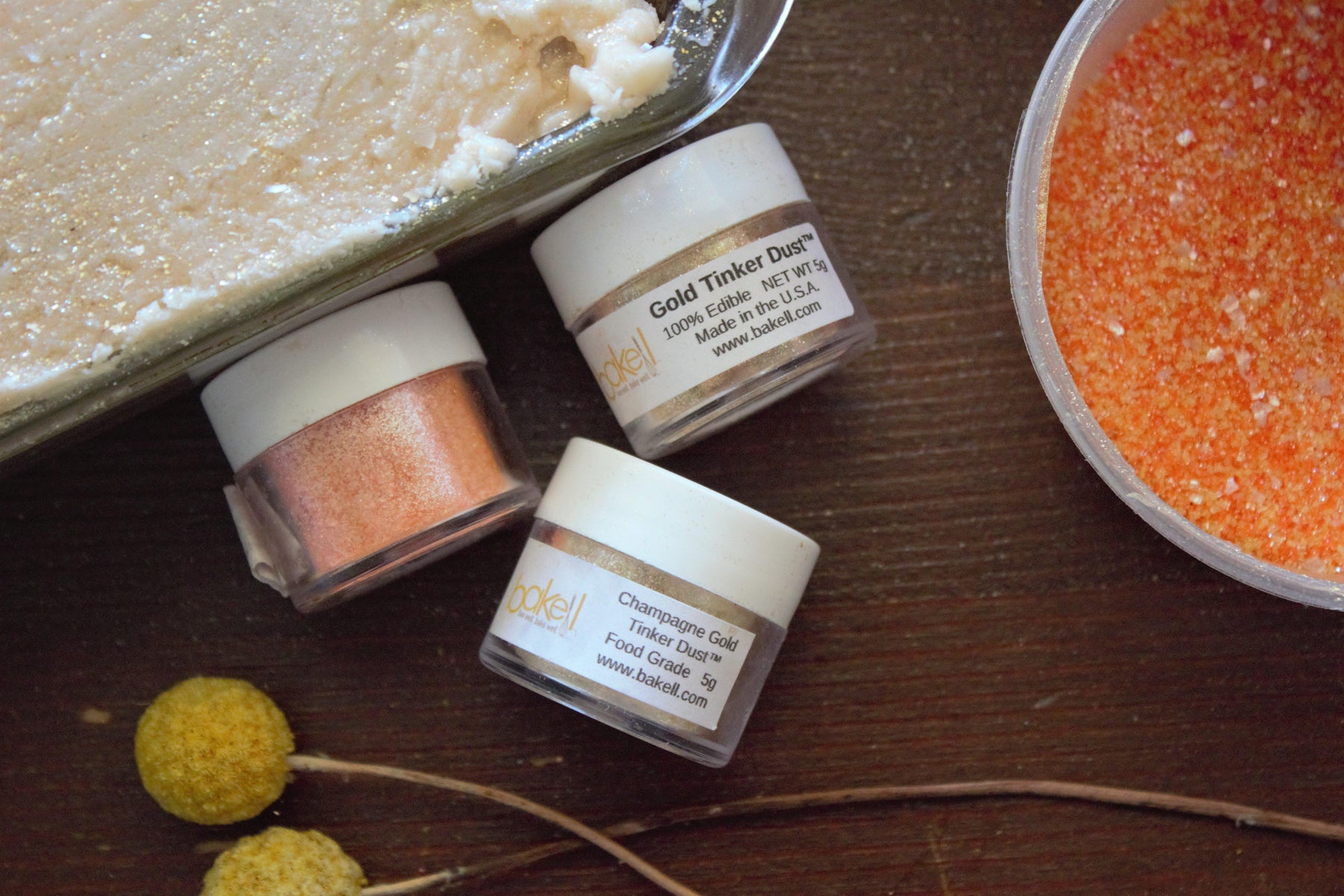 Gold and champagne edible glitter dust, orange sprinkles, and a dessert with gold shimmer.