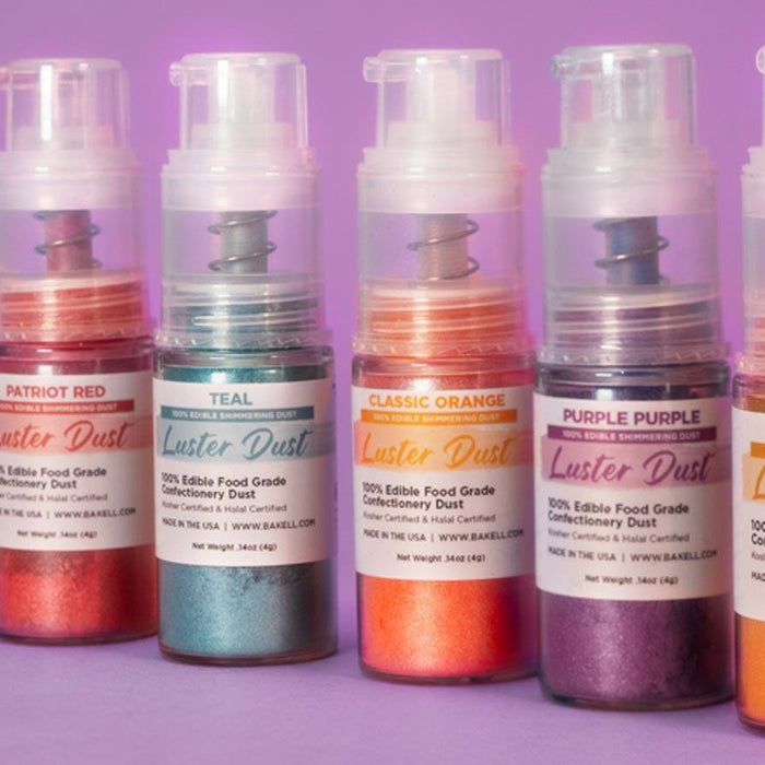 Six bottles of edible luster dust in various shimmery colors: green, red, teal, orange, purple, and gold.