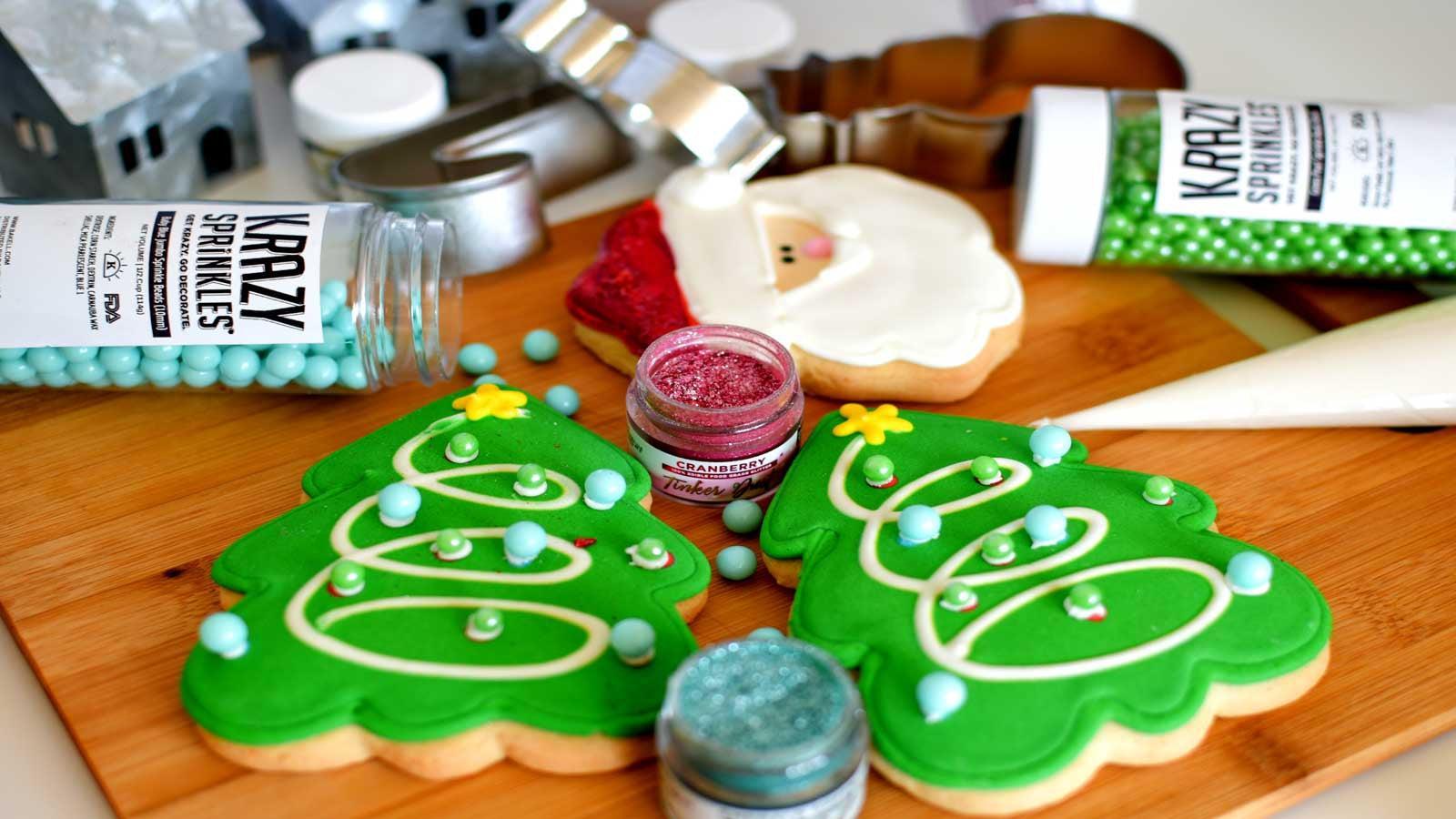 Decorated Christmas tree and Santa cookies with green, red, and blue sprinkles on a wooden board.
