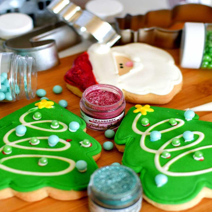 Decorated Christmas tree and Santa cookies with green, red, and blue sprinkles on a wooden board.
