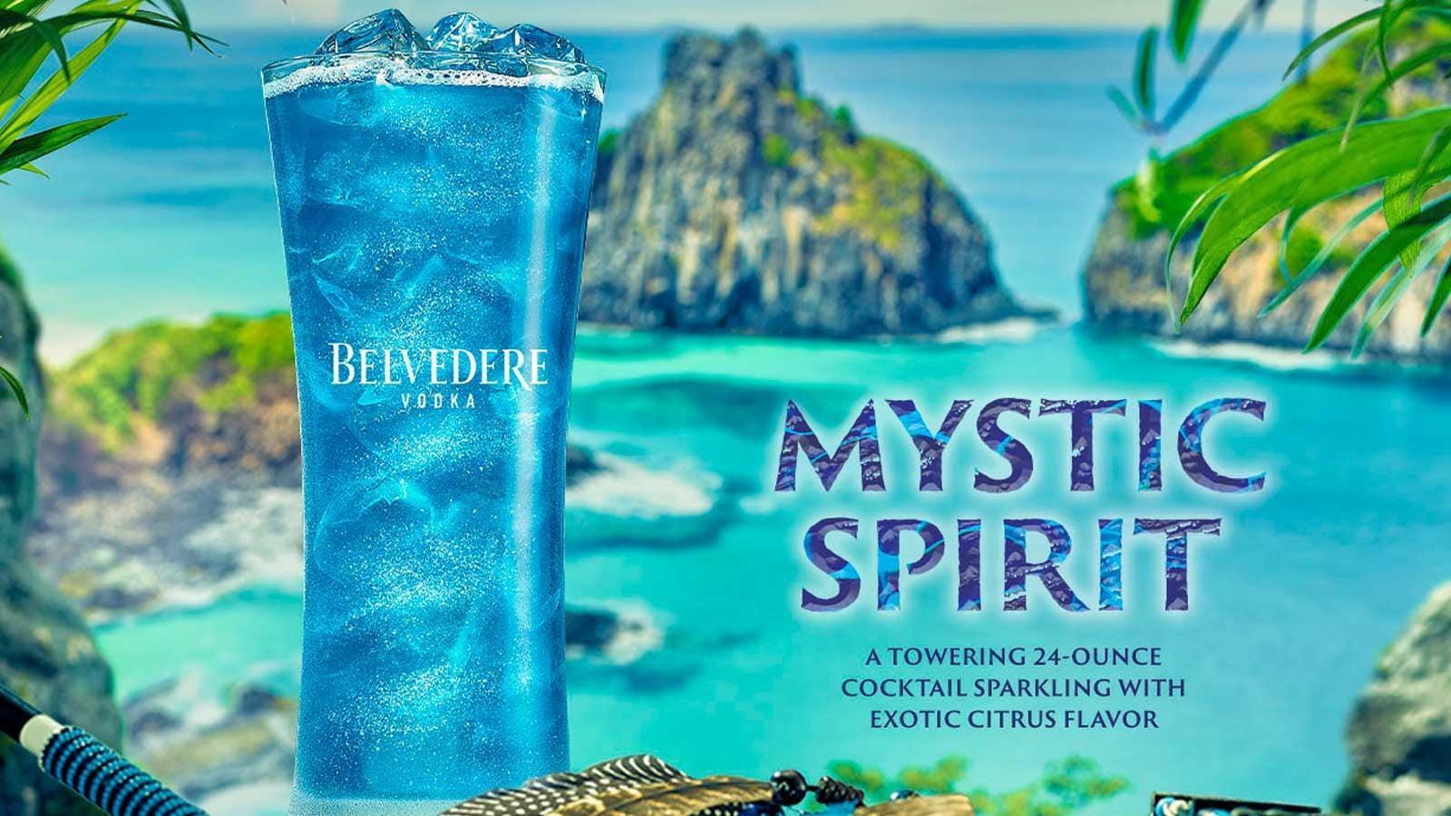 Tall blue Belvedere Vodka "Mystic Spirit" cocktail with ice, set against a tropical island and turquoise ocean.