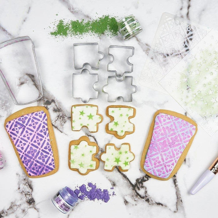 Decorated sugar cookies with puzzle and rectangular shapes, edible dusts, stencils, and cookie cutters.