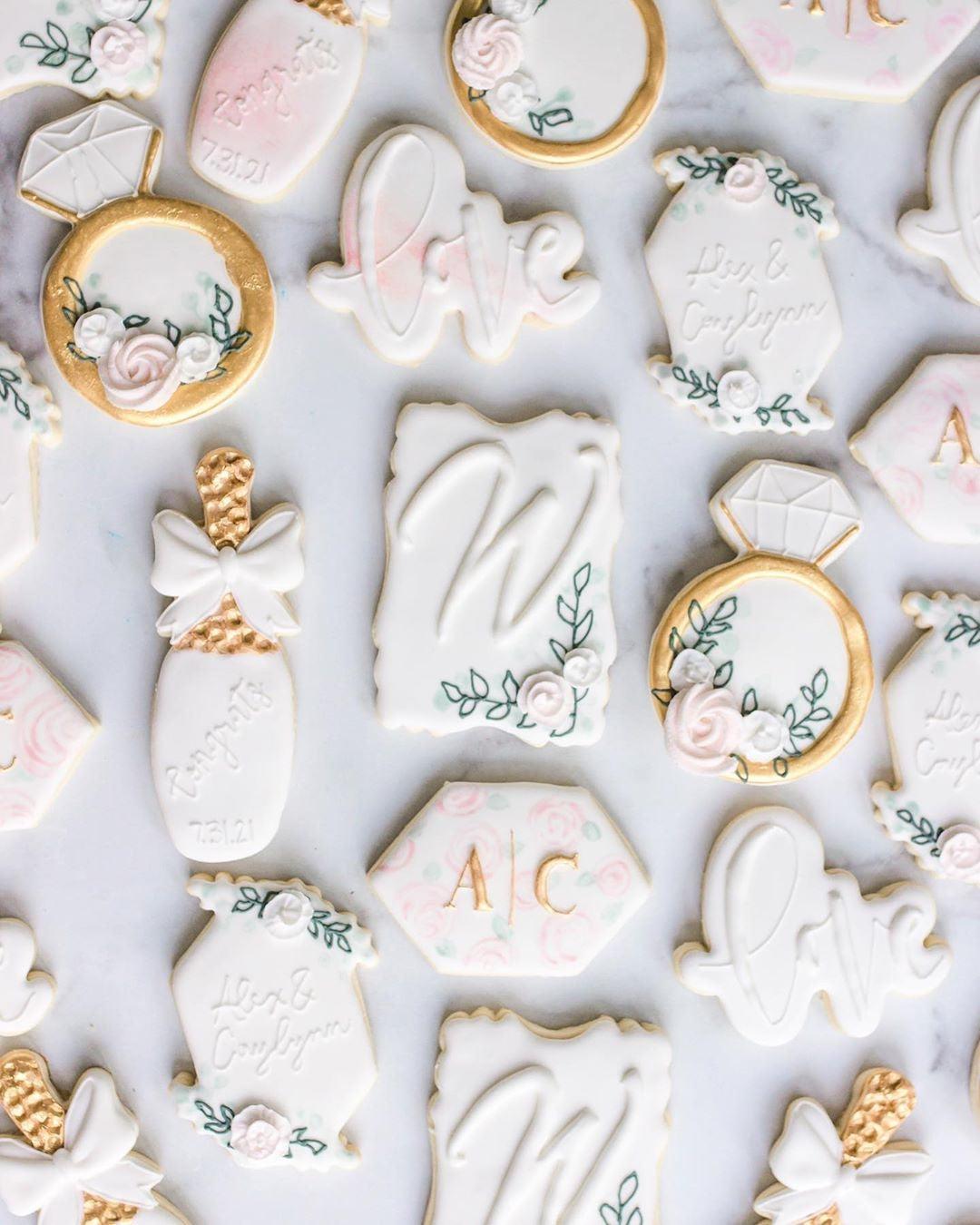 Elegant white and gold wedding-themed cookies with floral accents and personalized initials.