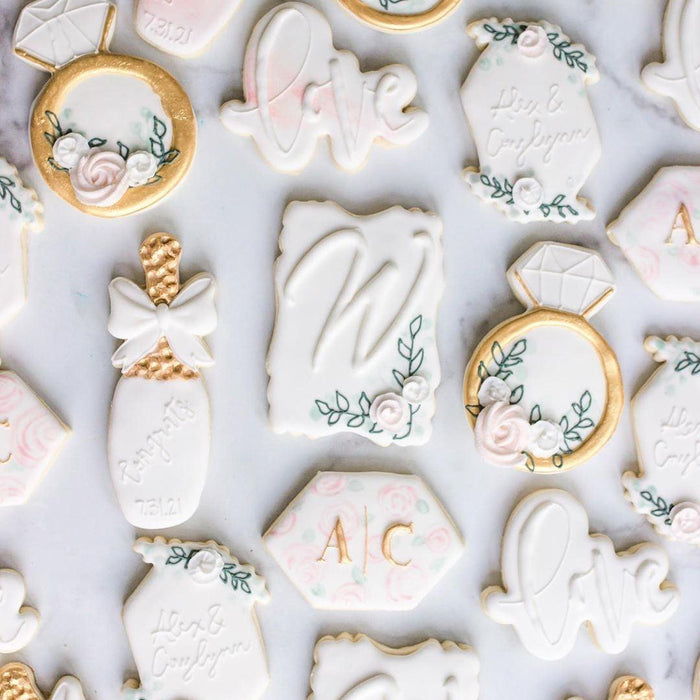 Elegant white and gold wedding-themed cookies with floral accents and personalized initials.
