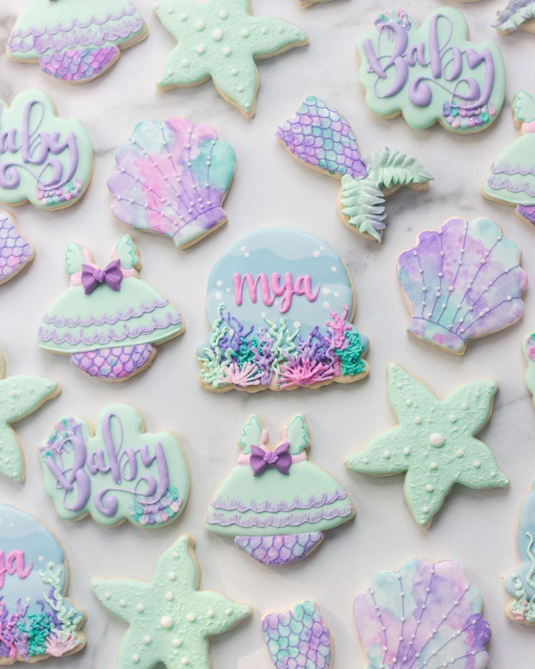 Mermaid-themed baby shower cookies: mint green starfish, purple shells, mermaid tails, and "Baby" script.