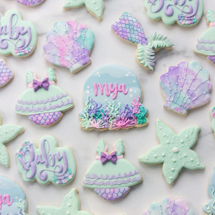 Mermaid-themed baby shower cookies: mint green starfish, purple shells, mermaid tails, and "Baby" script.