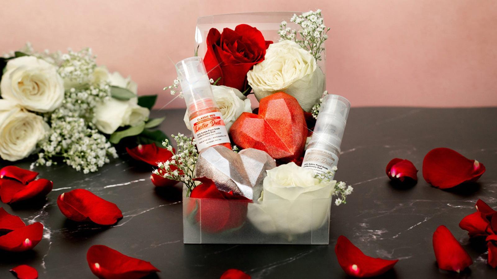 A clear box with red and white roses, two heart-shaped chocolates, and two glitter spray bottles.