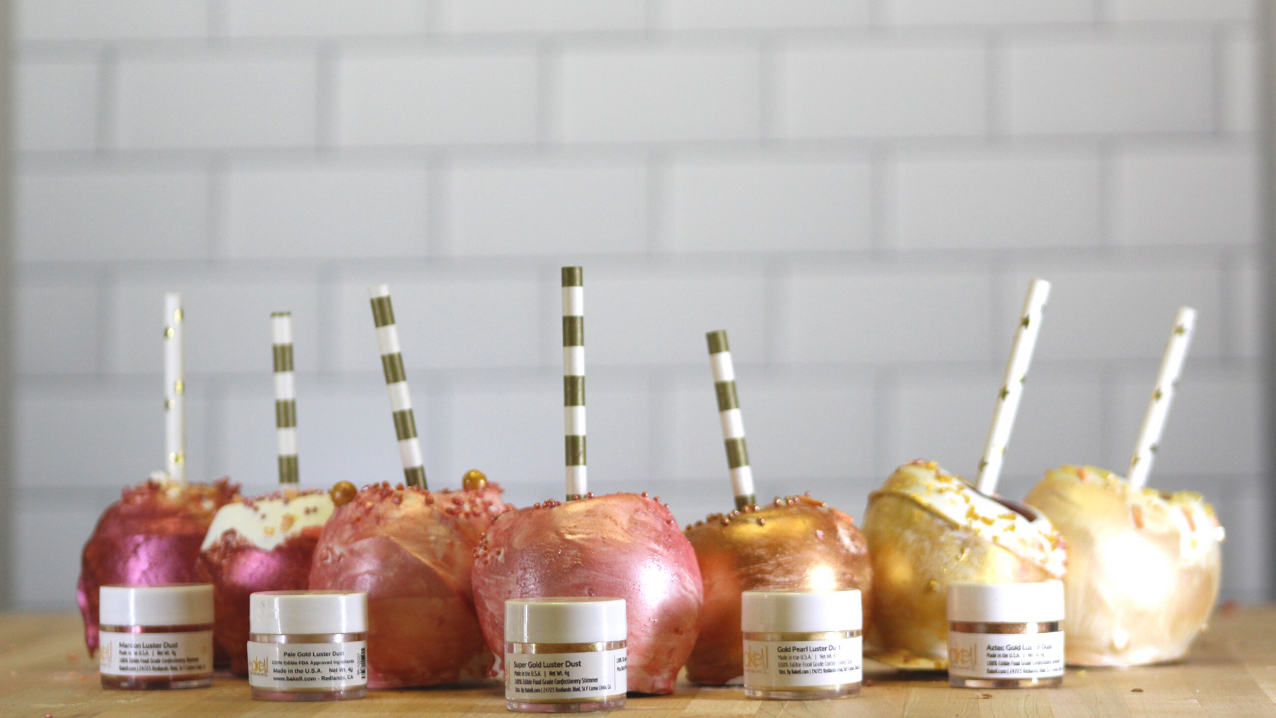 Shimmering gold and rose gold candy apples with striped straws, alongside jars of luster dust.