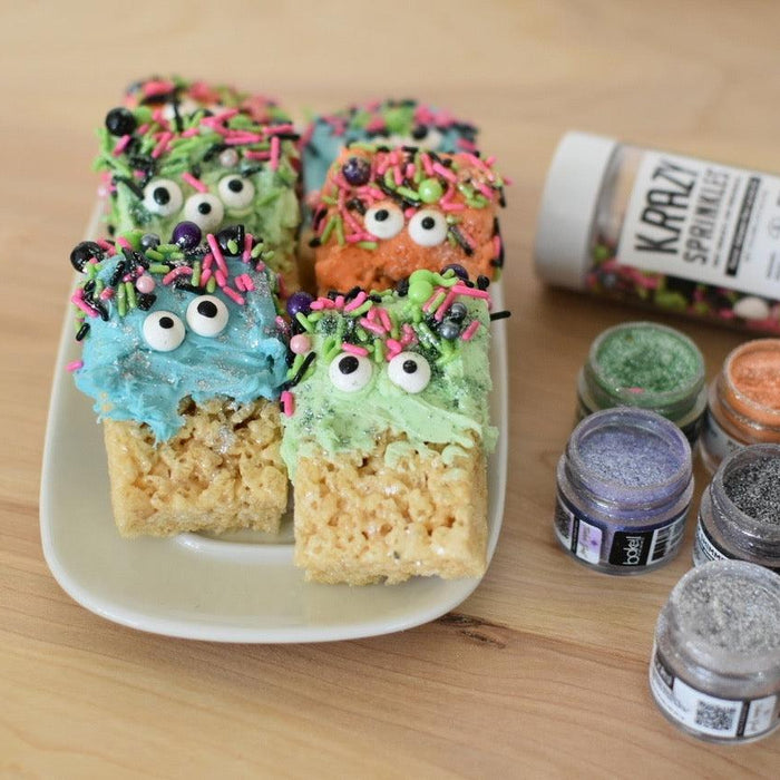 Colorful monster-themed Rice Krispie treats with candy eyes and sprinkles, next to edible glitter jars.