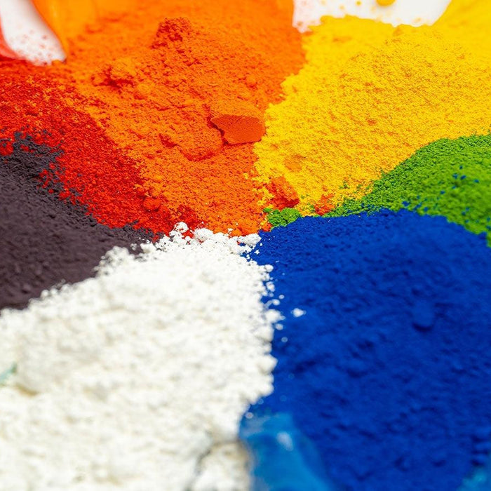 Vibrant piles of powdered pigments in red, orange, yellow, green, blue, black, and white.