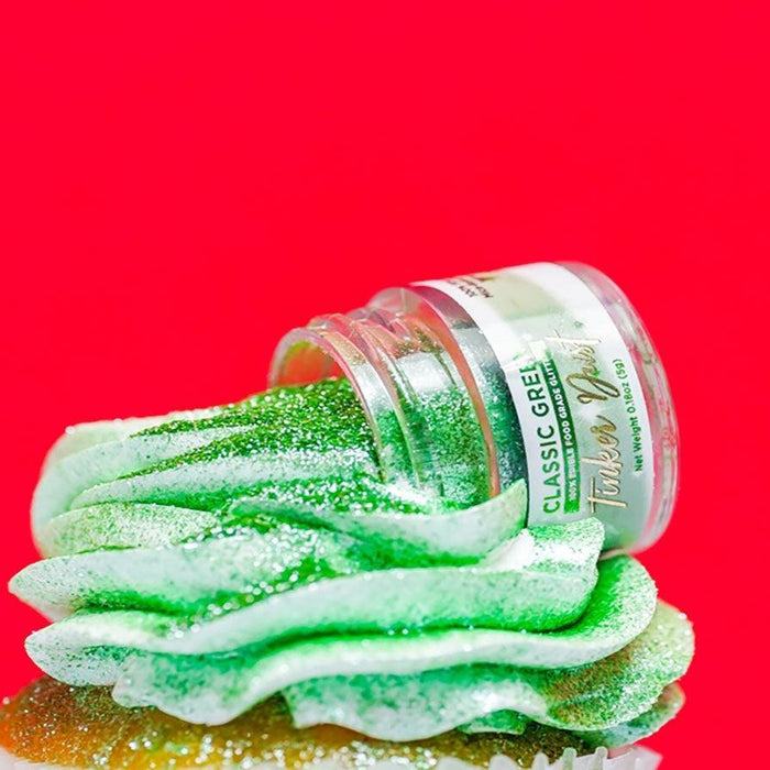 Green edible glitter spilling from a "Tinker Dust" jar onto a frosted cupcake.