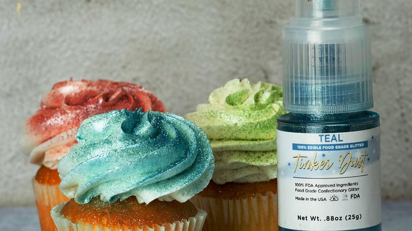Teal, red, and green glitter-dusted cupcakes next to a bottle of Teal Tinker Dust edible glitter.
