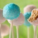 Assortment of pastel pink and blue cake pops, one with a bite taken out, revealing the cake inside.