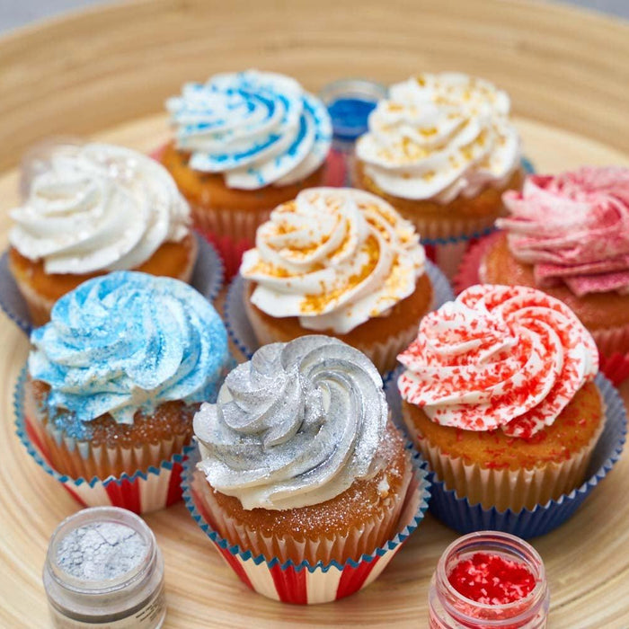Colorful cupcakes with various sprinkles and frosting swirls on a wooden tray, ready for decoration.