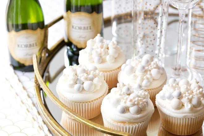 White frosted cupcakes with silver and white candy pearls, served with Korbel champagne on a gold tray.