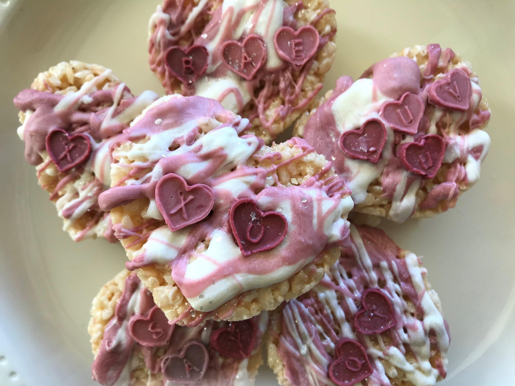 Valentine's Day crispy treats drizzled with pink and white icing, topped with heart-shaped candies.