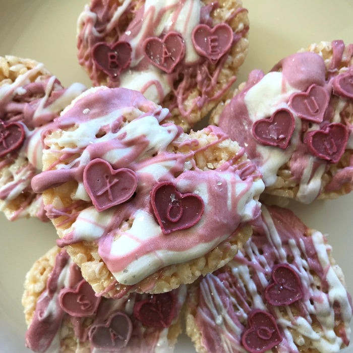 Valentine's Day crispy treats drizzled with pink and white icing, topped with heart-shaped candies.