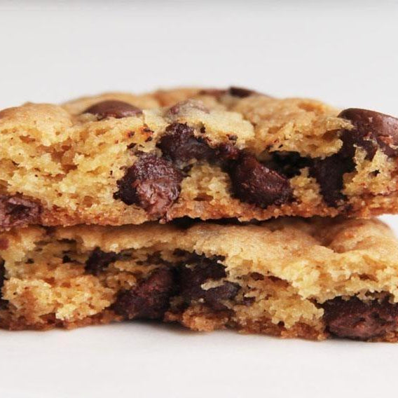 Two chewy, golden-brown chocolate chip cookies stacked, revealing a soft interior with melted chocolate.