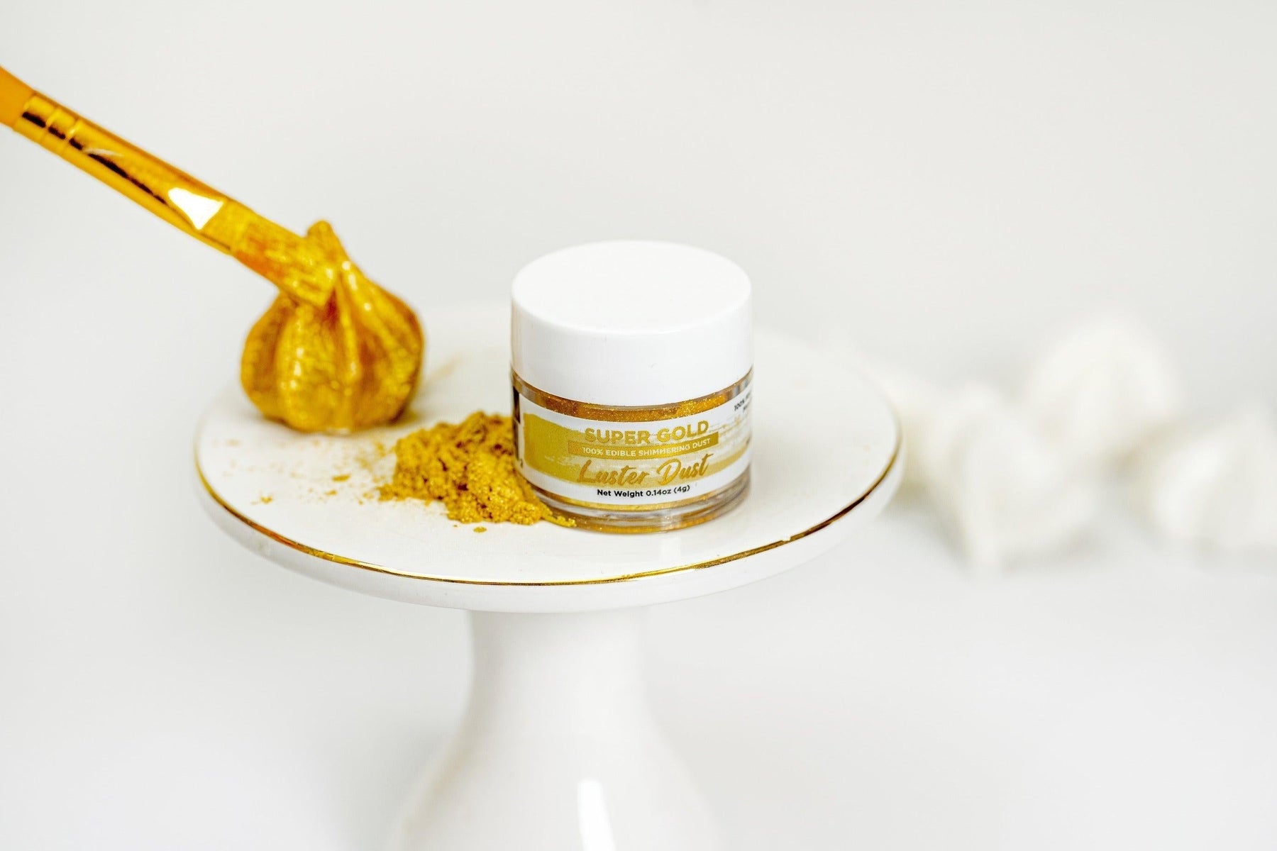 Super Gold Luster Dust jar with a pile of edible gold dust and a gold-painted pastry brush.