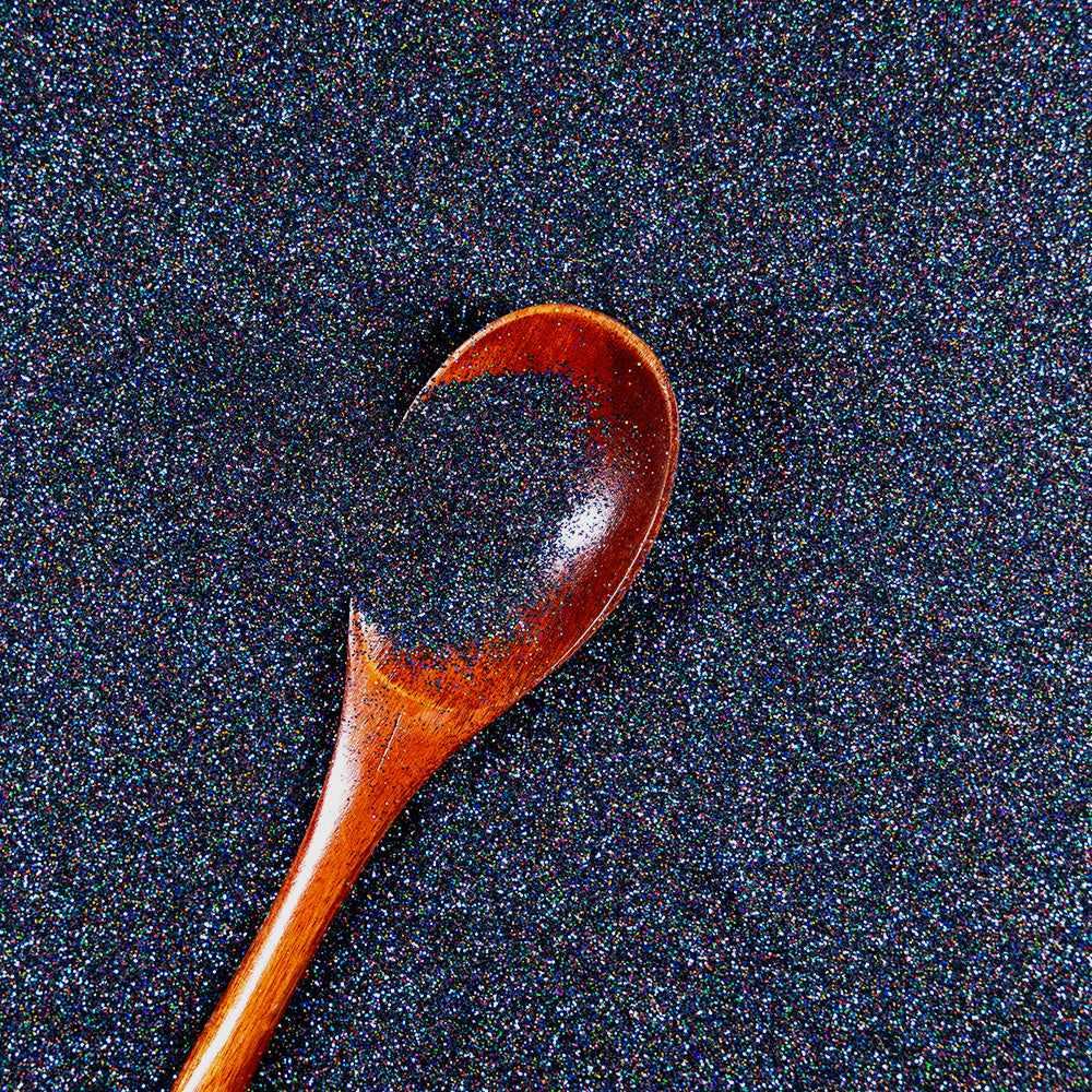 Black Magic Ultrafine Holographic Craft Glitter Dazzler Dust, dark blue polyester glitter with a wooden spoon.