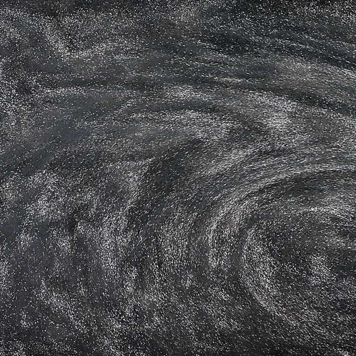 Swirling black edible glitter creating a shimmering, galaxy-like effect in a beverage.