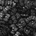 Pile of shiny black spider-shaped sprinkles for baking and decorating.