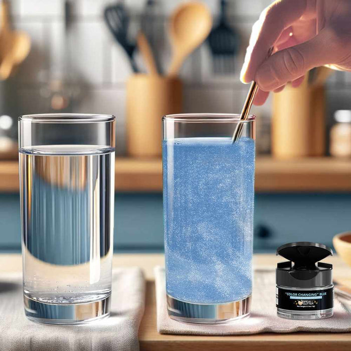 Hand stirring blue color-changing brew glitter into a tall glass of water, with a clear glass and glitter jar nearby.