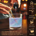 Blue iridescent edible glitter being poured into a glass of liquid, creating a holographic, shimmery effect.