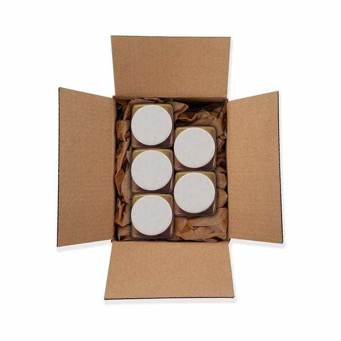Open cardboard box filled with six small jars of Bright Gold Tinker Dust® Glitter, cushioned by brown crinkle paper.