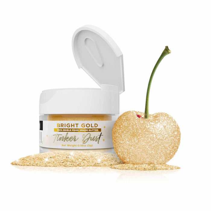Open 5g jar of Bright Gold Tinker Dust edible glitter next to a gold-dusted cherry and a pile of glitter.