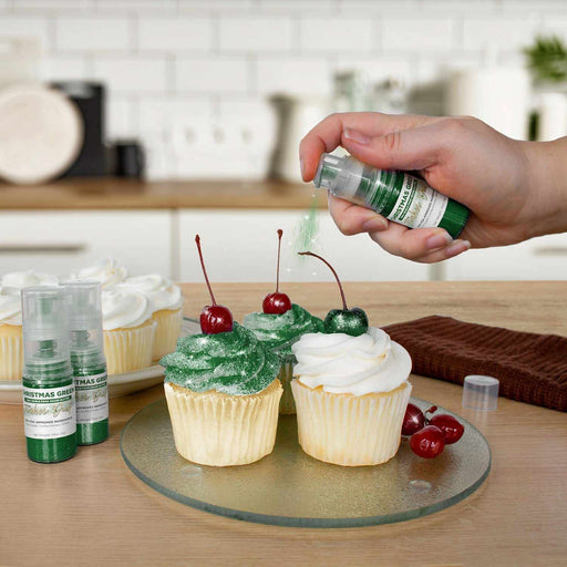 Three cupcakes being sprayed by a Christmas Green colored Edible Glitter 4 gram pump. | bakell.com