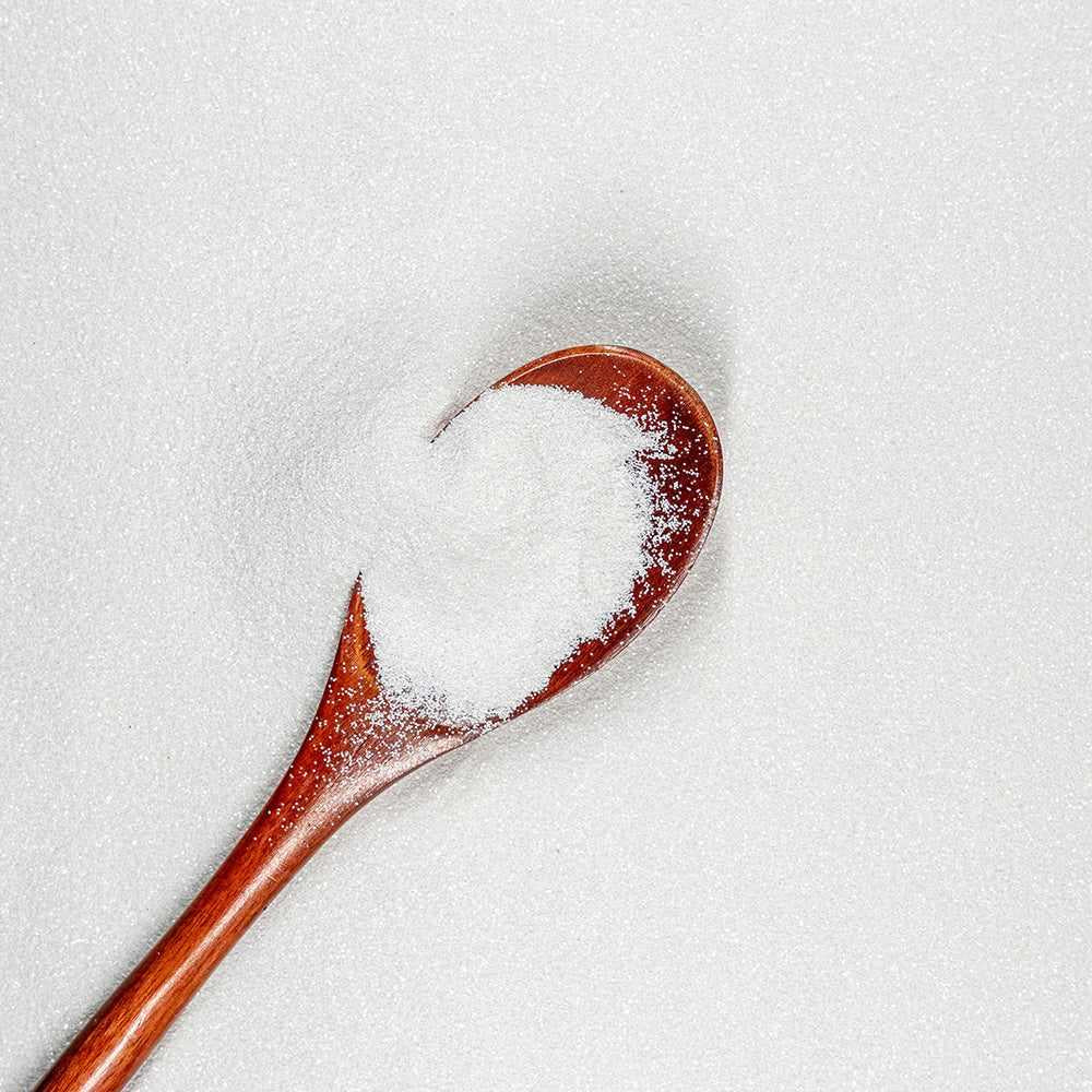 Ultrafine matte UV reactive snow white craft glitter on a wooden spoon, surrounded by more glitter.