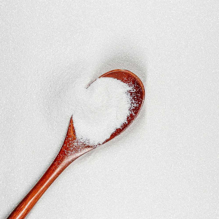 Ultrafine matte UV reactive snow white craft glitter on a wooden spoon, surrounded by more glitter.