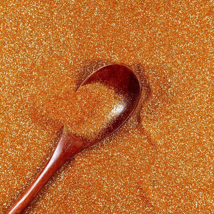 Golden Egg ultrafine UV reactive metallic craft glitter with a wooden spoon.