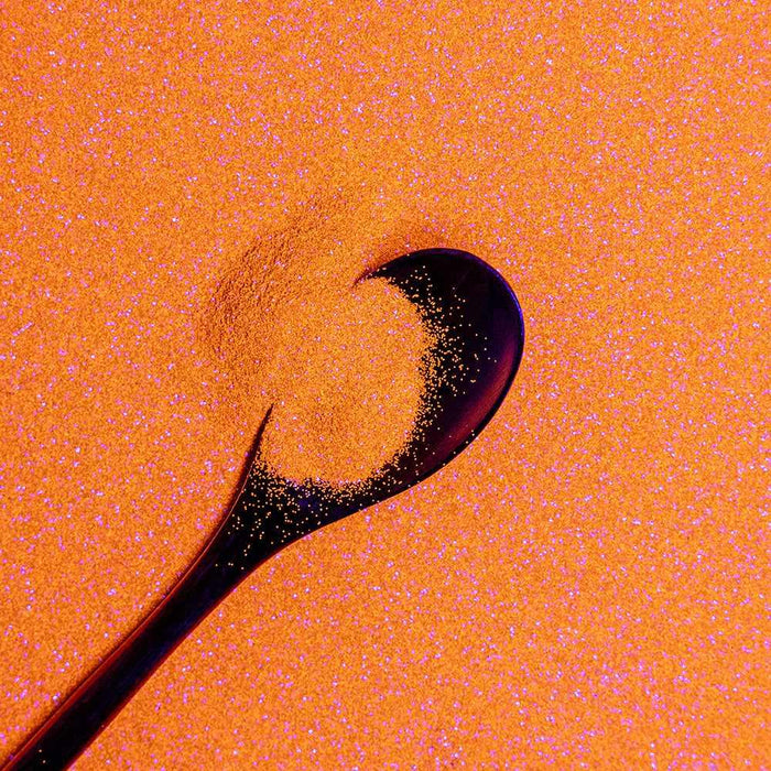 Golden Egg ultrafine UV reactive metallic craft glitter with a dark spoon.