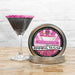 Hot pink rimming sugar in a metal tin next to a martini glass with a pink sugar rim.