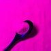 Hot pink ultrafine UV reactive iridescent craft glitter in a spoon, against a pile of glitter.