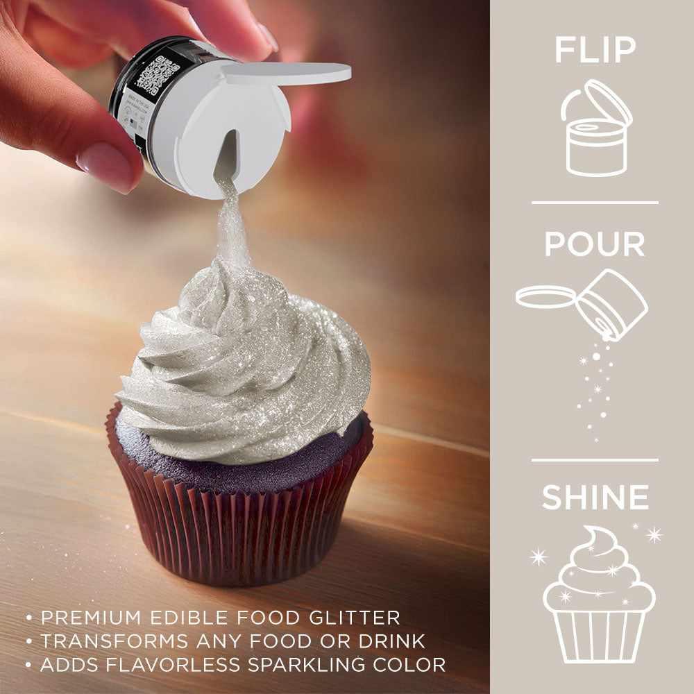 Hand sprinkling shiny ivory Tinker Dust edible glitter from a shaker onto a frosted cupcake.