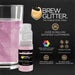 Light pink edible beverage glitter in a mini spray pump next to a glass of sparkling pink drink.