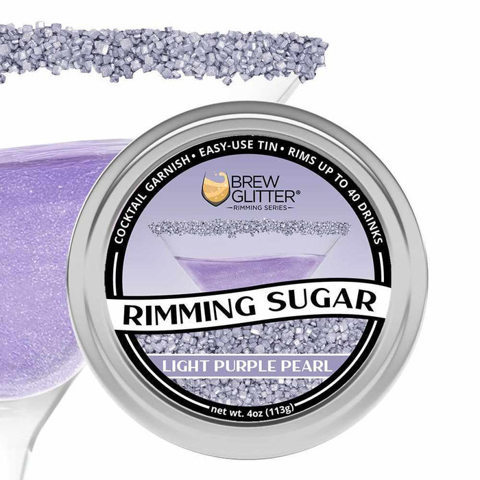 Light purple pearl rimming sugar in a round aluminum tin, with a cocktail glass rimmed with sugar in the background.