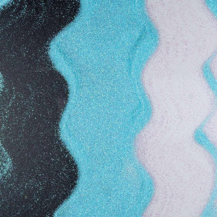 Wavy lines of light teal iridescent ultrafine craft glitter on black and white surfaces.