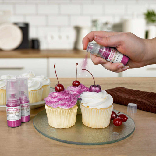 Three cupcakes being sprayed by a Neon Pink color Edible Glitter 4 gram pump. | bakell.com