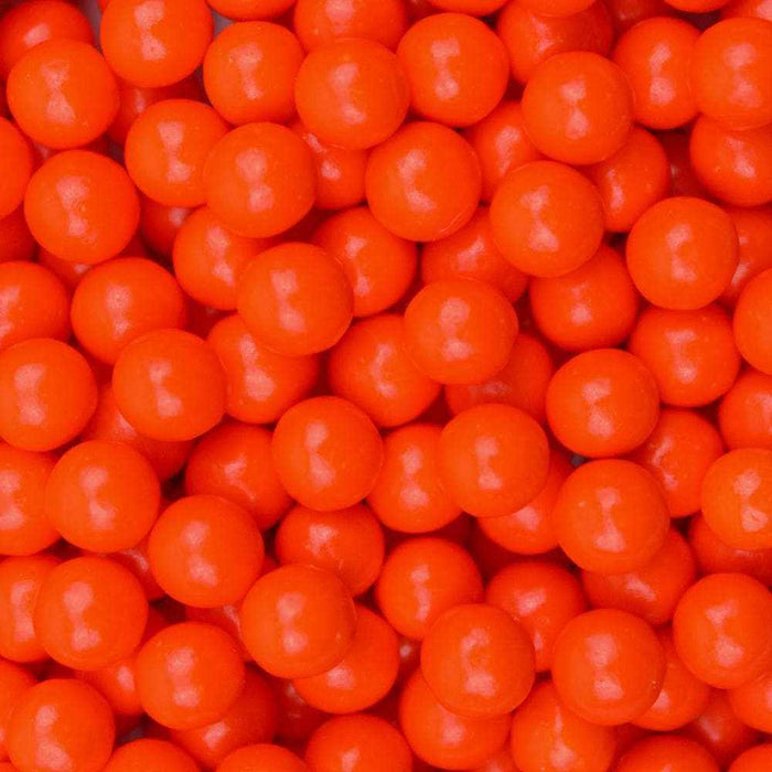 Pile of bright orange 8mm edible pearl beads for bulk dessert decoration.